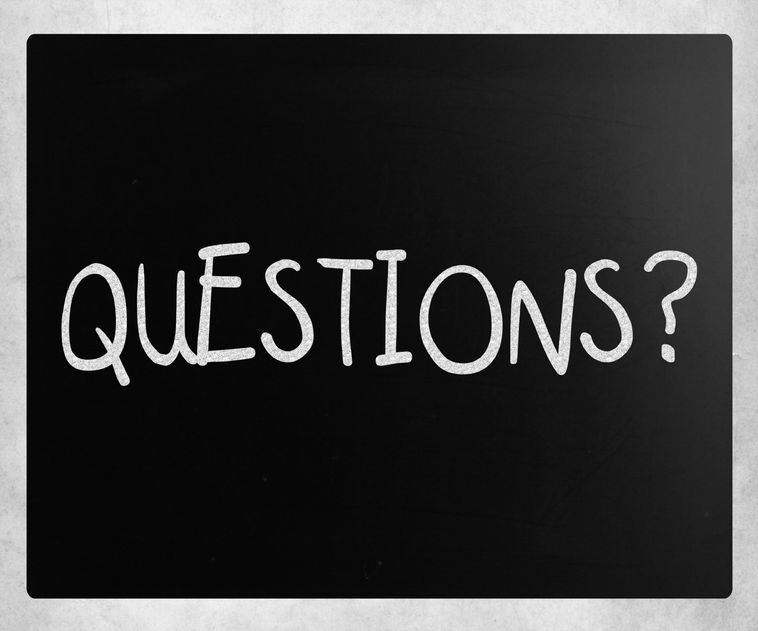 The word "questions?" written on a chalk board.