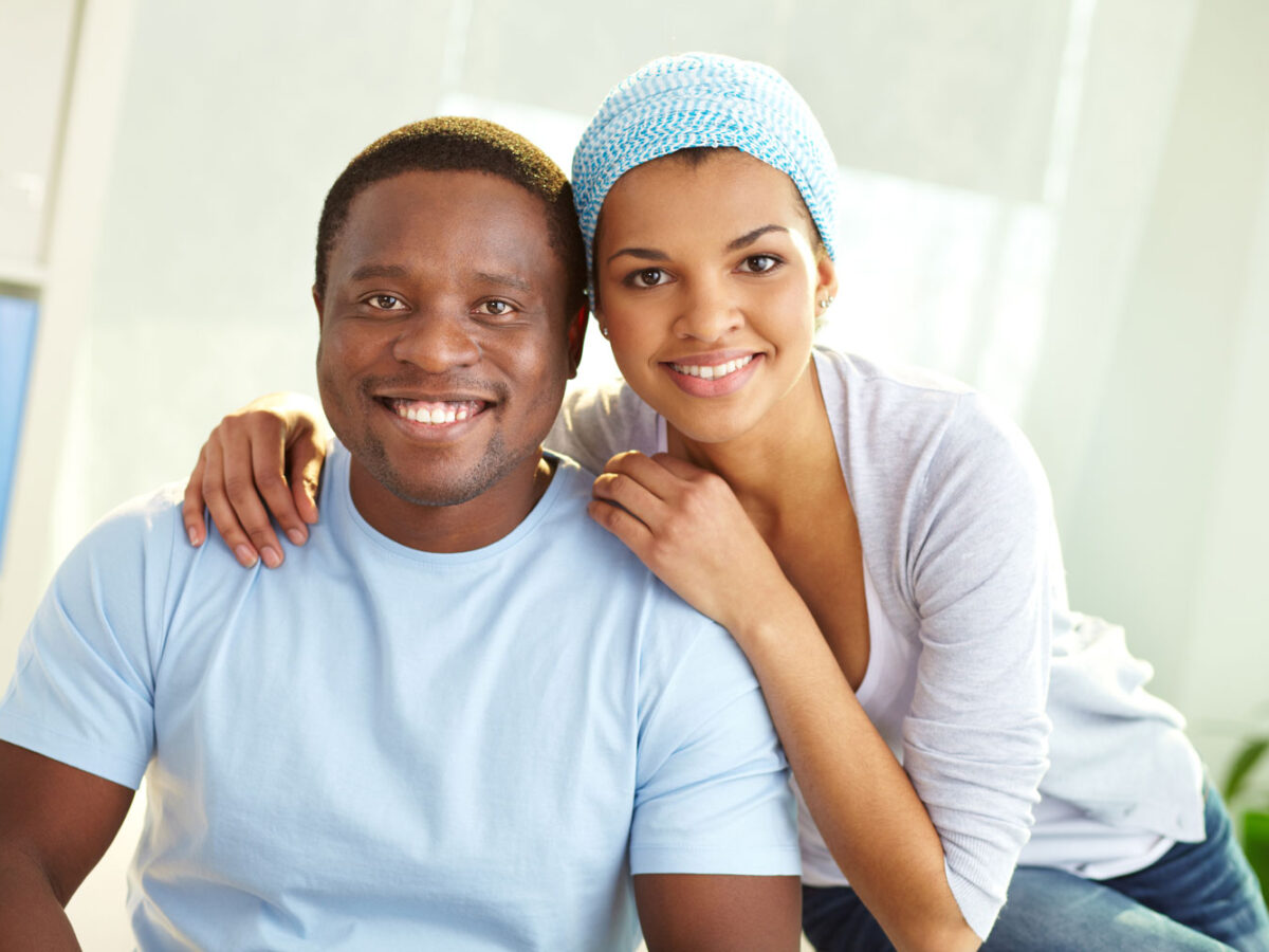 African American couple smiling into the camera.
