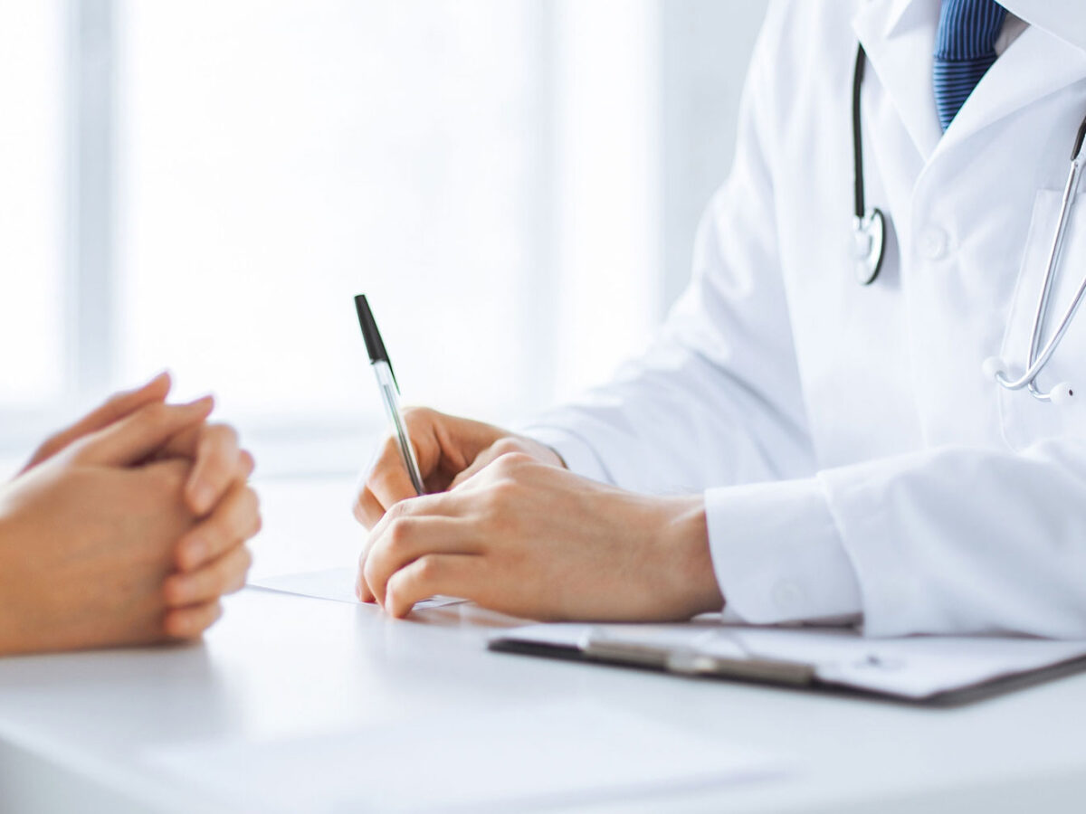 Close up of the hands of a doctor and a patient talking at a table.