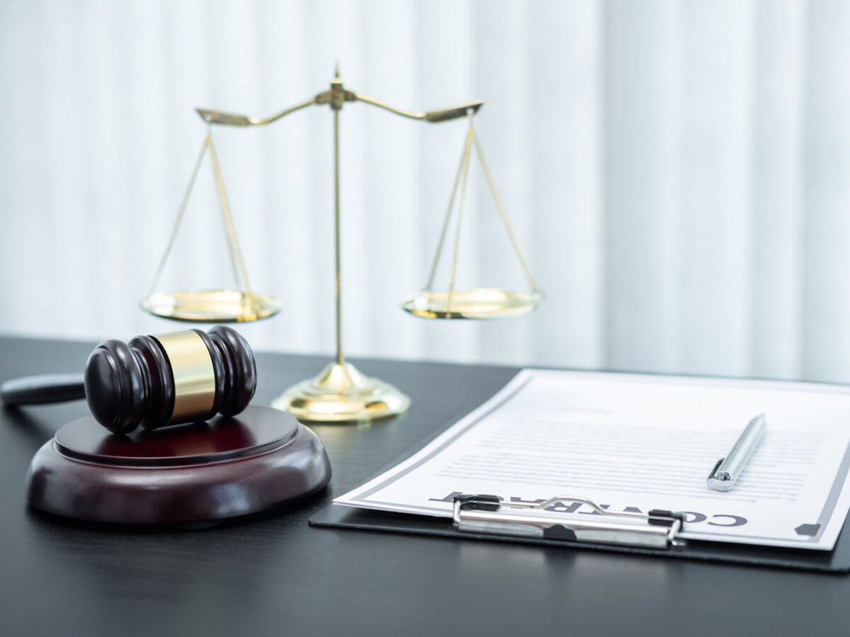 A judges gravel with justice scales and paper on a table.