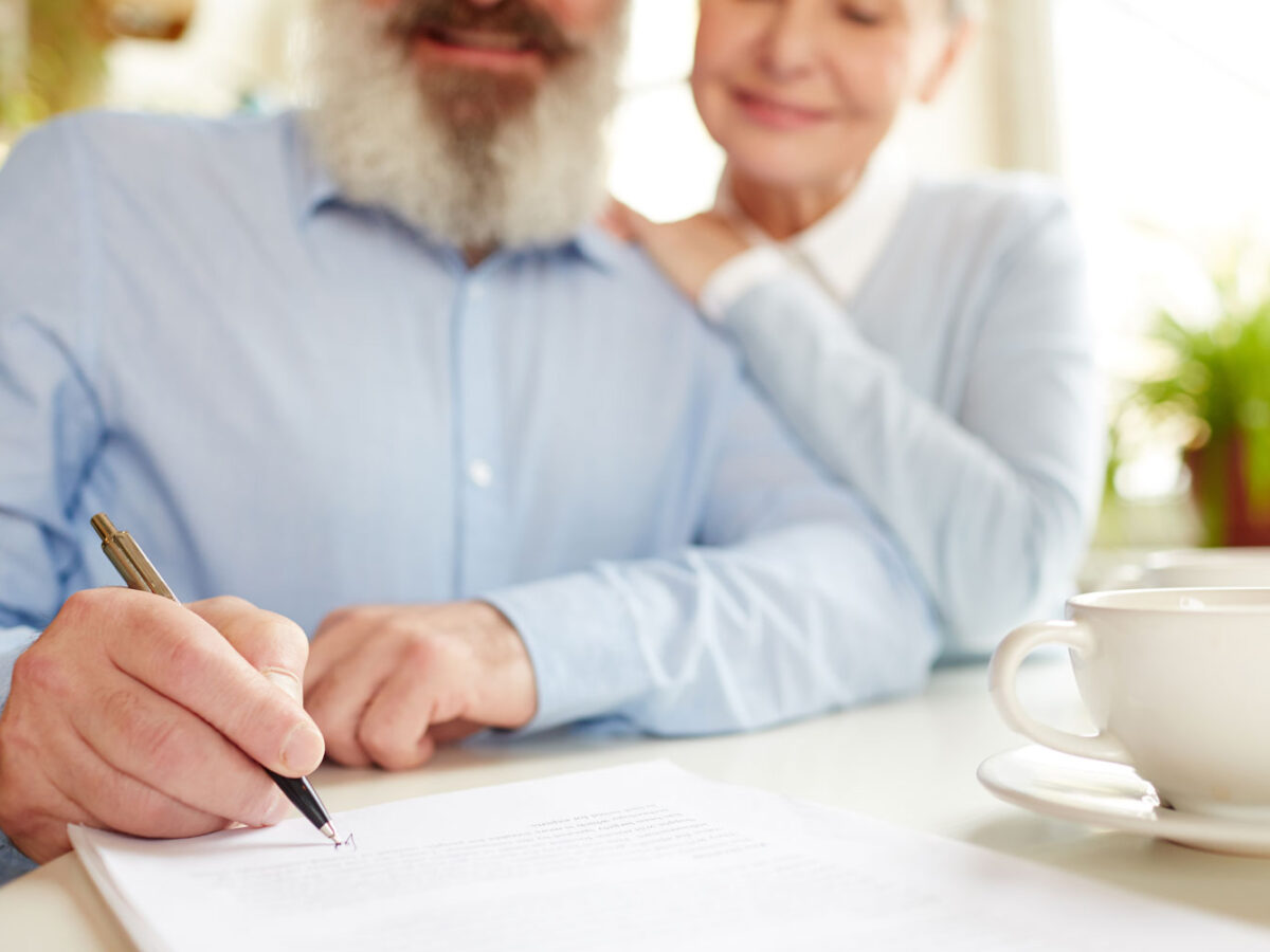 Elderly couple signing papers.