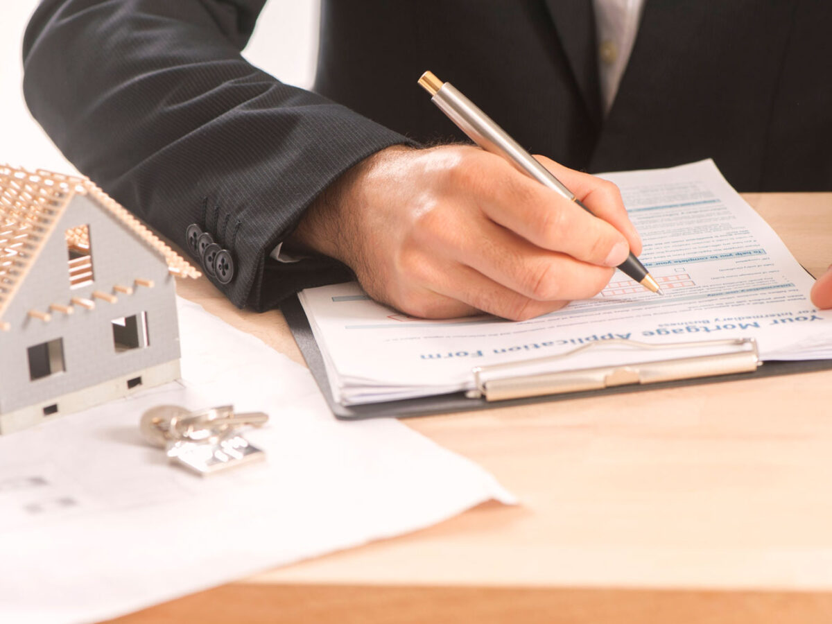 Man is a suit signing documents.