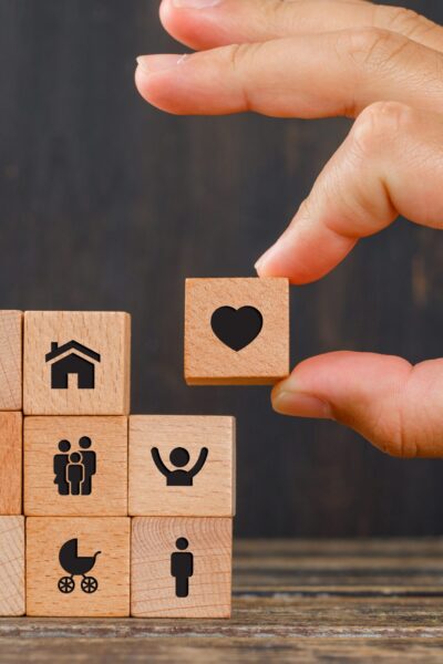 Relationship concept on wooden background side view. hand holding wooden cube with heart icon.